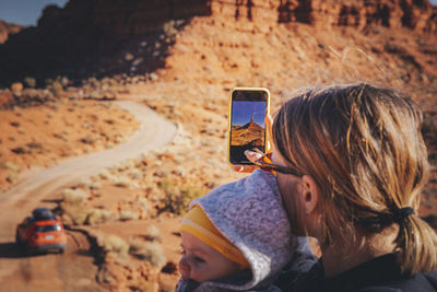 A woman with a child is taking pictures in valley of the gods, utah