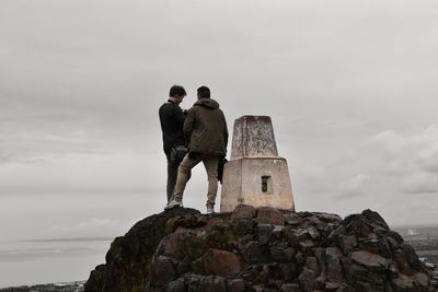 Rear view of man standing on rock against sky