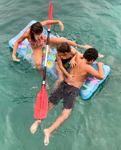 High angle view of siblings on inflatable raft in lake