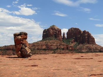 Rock cairn on red mountains against sky