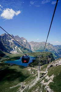 View of overhead cable car and mountains against blue sky