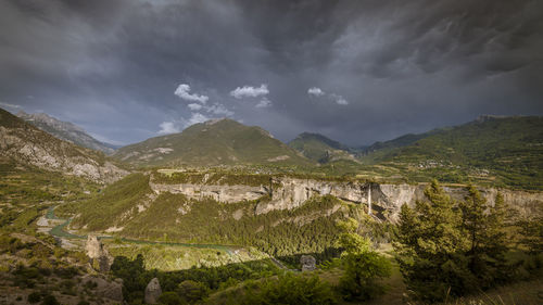 Scenic view of mountains and waterfall against sky