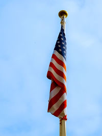 Low angle view of american flag against blue sky