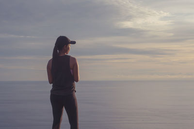 Full length of woman standing on sea against sky during sunset