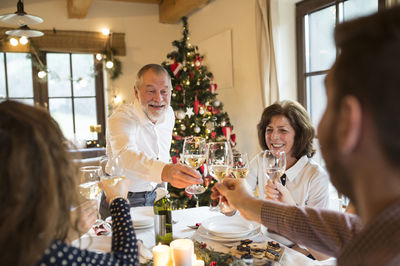 Senior man clinking glasses with family at christmas dinner