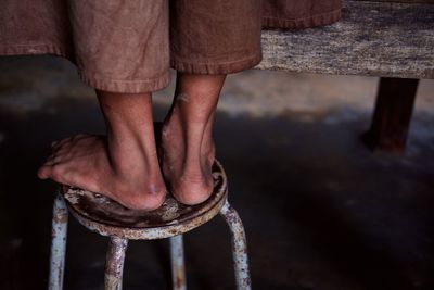 Low section of man standing on rusty stool