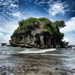 People on beach against cloudy sky