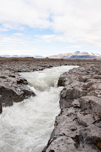 River flowing through volcanic rocks. snow-capped mountain in the background.