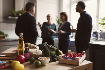 Food on table against friends talking in kitchen