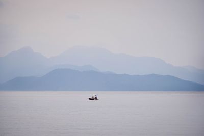 Boat sailing on sea against mountains