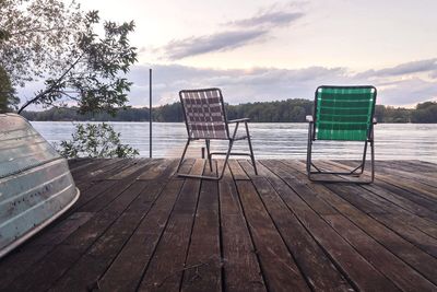 Empty chair by sea against sky