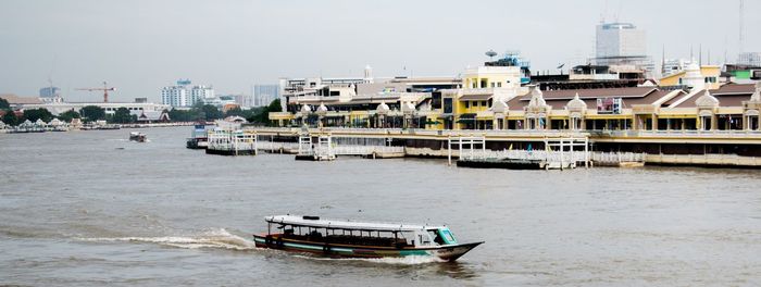 Boat on river against buildings in city