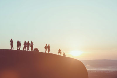 Silhouette people standing on mountain against sky during sunrise