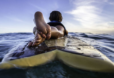 Rear view and close up of a 3 years old surfer on wooden surfboard