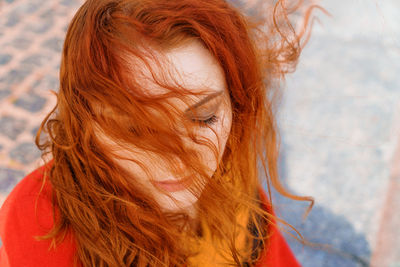 Close-up portrait young caucasian woman with red curly hair in a red coat person