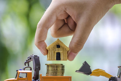 Cropped hand stacking model house on coins