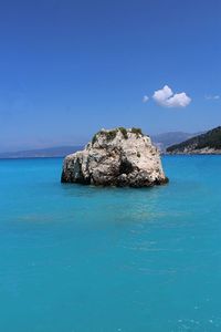 Scenic view of rocks in sea against blue sky