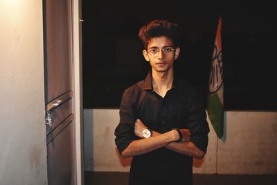 Portrait of young man standing by door against sky at night