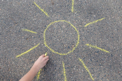 Cropped hand drawing sun on road 