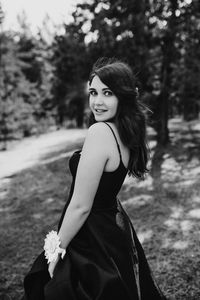 Young woman standing against trees