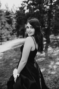 Young woman standing against trees