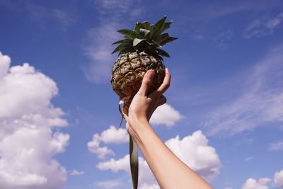 Low angle view of person holding ice cream against sky