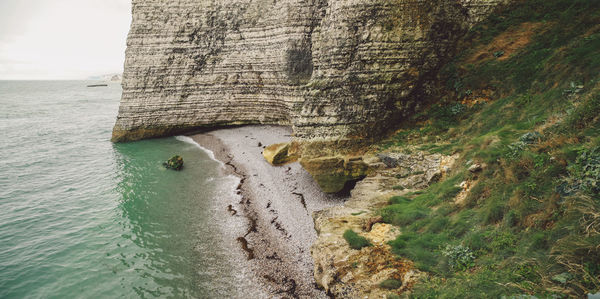 Cliff by sea against sky