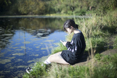 Young woman sitting by lake