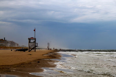 Lighthouse on beach by sea against sky. italy