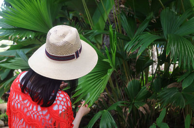 Rear view of woman with hat holding leaves outdoors