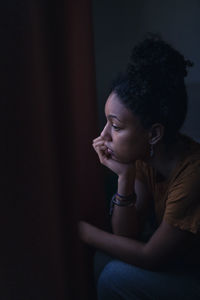 Pensive young woman sitting at home