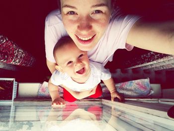 High angle portrait of happy mother with son standing by window at home