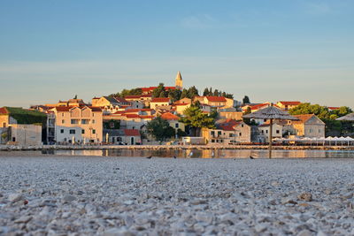 Houses by river in town against sky