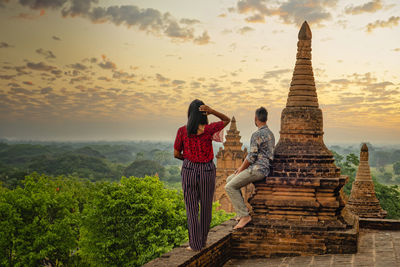 Rear view of woman standing against sky during sunset