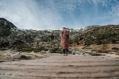 Rear view of man standing on mountain against sky