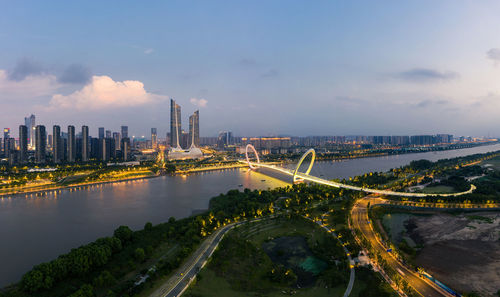 Bridge over river amidst buildings in city against sky