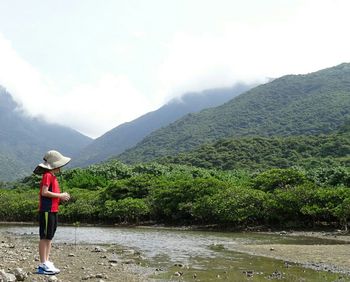 Full length of woman standing on mountain against sky