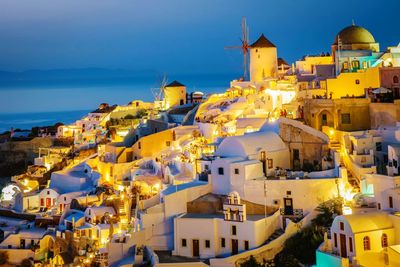 Illuminated houses by sea at dusk