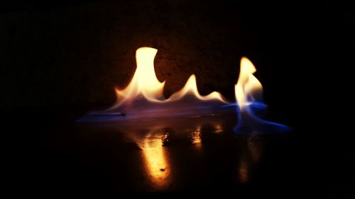 Close-up of burning candle against black background
