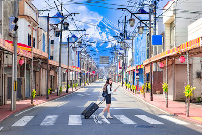 Woman walking on road along buildings