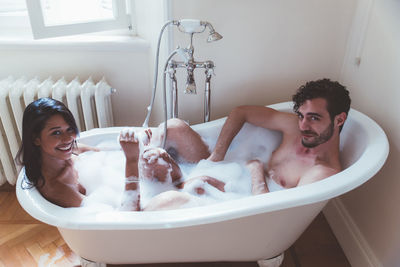 High angle portrait of smiling couple sitting in bathtub