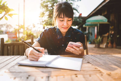 Woman using mobile phone while sitting on table