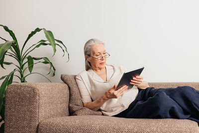 Portrait of young woman using mobile phone while sitting on sofa at home