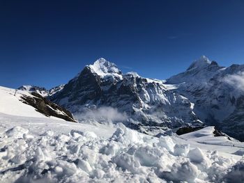 Scenic view of snowcapped mountains against clear blue sky