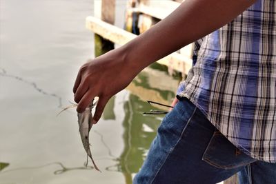 Midsection of man holding fish in water