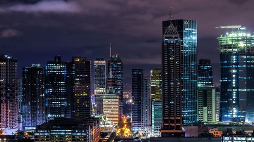 Illuminated buildings in city against sky at night