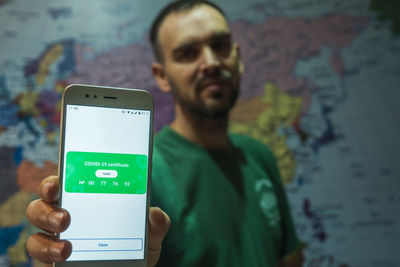 A man holding a smartphone in his hand with a valid covid-19 vaccination certificate 