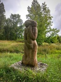 Statue amidst trees on field against sky