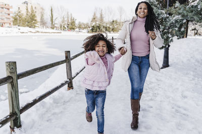 Full length portrait of smiling woman standing on snow covered landscape during winter