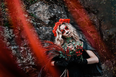 Closeup portrait of calavera catrina. young woman with sugar skull makeup and red flowers. dia